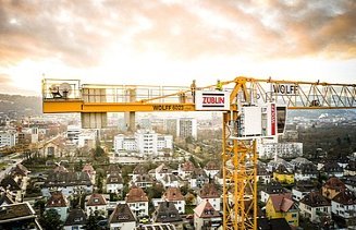 Yellow crane with Züblin and Wolff logos in front of a city panorama