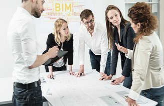 Group of people standing around a table and discussing a construction plan