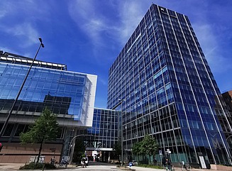 T-formede glasfacader på en kontorbygning med en vej, der løber under den 