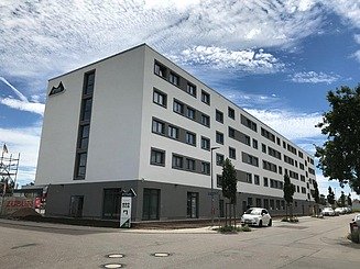 Billede af et hotel med lys facade og grå sokkel på hjørnet af to gader