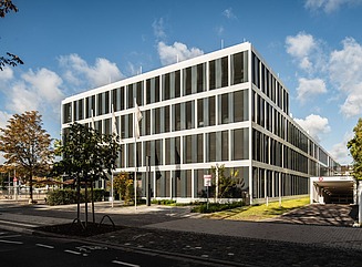 Office building with large windows Traffic signs and parked car, trees in the foreground