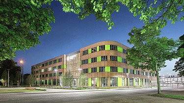 Gebäude bei Dämmerung mit Holzfassade und grünen Elementen